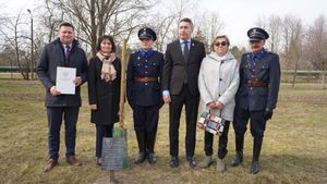 Grupa kilku mężczyzn i kobiet stoi obok siebie przy miejscu wkopywanego dębu.