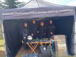 Policjanci stoją pod namiotem z napisem Komenda Powiatowa Policji powiatu Łódzkiego wschodniego.