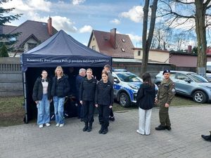 Grupa młodych ludzi stoi przed policyjnym namiotem.