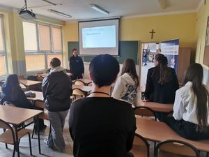 Policjantka stoi na środku klasy przed grupą młodych ludzi.