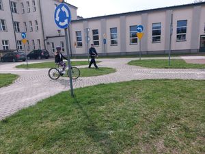 Policjant idzie za osobą jadącą na rowerze.