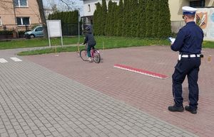 Policjant idzie za osobą jadącą na rowerze.