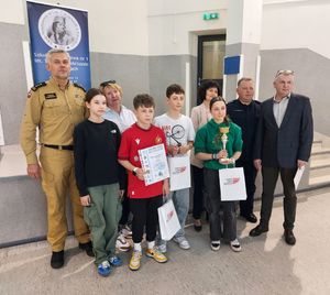 Policjant, strażak i nauczyciele stoją przy grupie młodych osób.