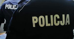 Dwóch policjantów odwróconych tyłem i napis na plecach mundurów Policja.