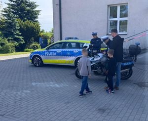 Policjanci ruchu drogowego uczestniczą w pikniku rodzinnym na terenie szkoły.