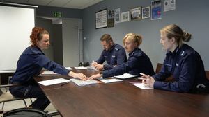 Policjanci i pracownik starostwa siedzą przy stole i oceniają prace plastyczne.