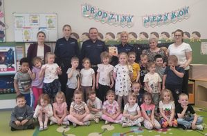 Policjanci stoją z grupą dzieci i ich opiekunów.