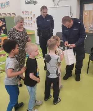 Policjant rozdaje przedszkolakom odblaski.