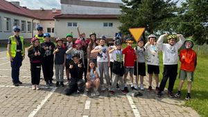 Grupa dzieci stoi obok policjantów.