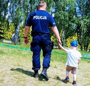 Policjant prowadzi małe dziecko.