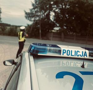Policjantka stoi przy drodze i mierzy prędkość.