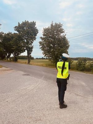 Policjantka stoi przy drodze i mierzy prędkość.