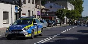 Policyjny radiowóz jedzie przed uczestnikami rajdu rowerowego.