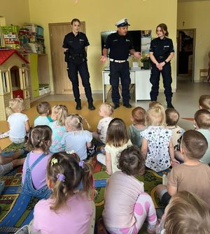 Dwie policjantki i policjant stoją w sali w której siedzą dzieci.