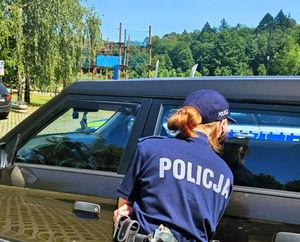 Policjantka zagląda przez szybę samochodu.