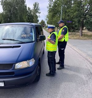 Policjant i strażnik ochrony kolei kontrolują samochody.