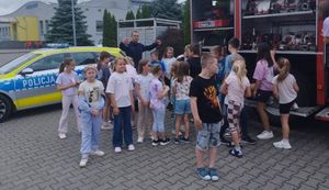 Policjant i strażacy na spotkaniu z dziećmi przebywającymi na półkoloniach.