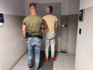 Policjant stoi z zatrzymanym mężczyzną.
