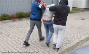 Policjanci prowadzą zatrzymanego mężczyznę.