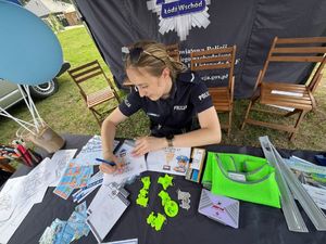 Policjantka siedzi przy stoliku i pisze.