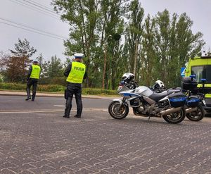 Dwóch policjantów ruchu drogowego stoi przy drodze.