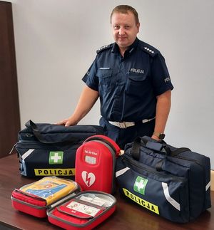Policjant stoi obok sprzętu medycznego ustawionego na stoliku.