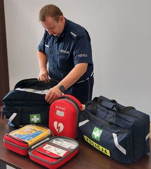 Policjant stoi obok sprzętu medycznego ustawionego na stoliku.