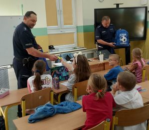 Policjanci rozdają odblaski uczniom.