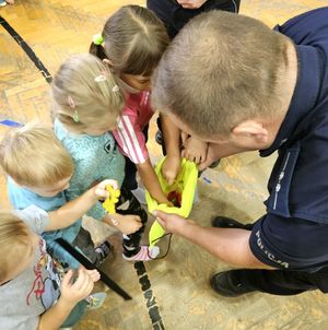 Policjanci rozdają odblaski przedszkolakom.