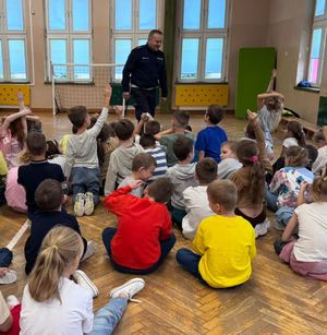 Policjant stoi na środku sali, przed nim siedzą dzieci.