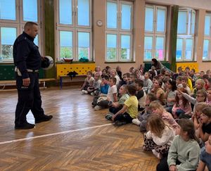 Policjant stoi na środku sali, przed nim siedzą dzieci.