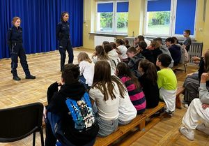 Policjantki stoją na środku sali, przed nimi siedzą dzieci.