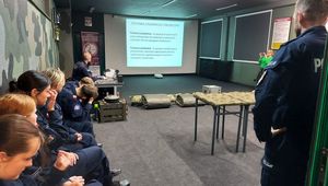 Dwóch policjantów szkoli uczniów klas mundurowych z musztry policyjnej.