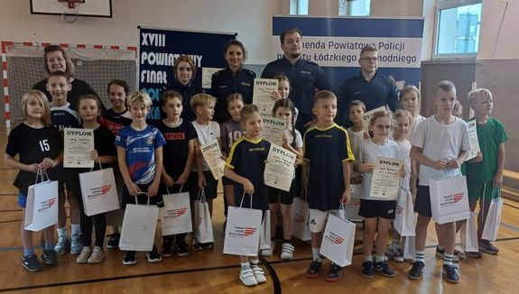 Dzieci stoją na środku hali sportowej razem z policjantami, panią dyrektor szkoly i panią wicestarostą.