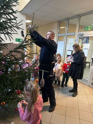 Policjanci i dzieci stroją choinkę.