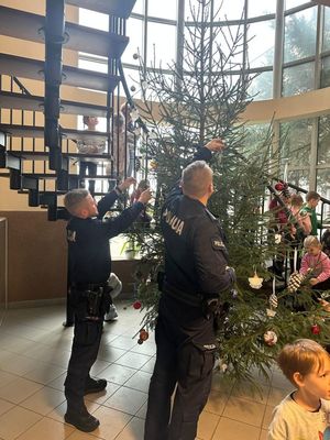 Policjanci i dzieci stroją choinkę.