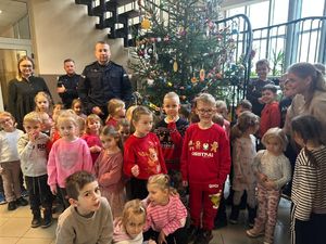 Policjanci stoją razem z przedszkolakami przy ustrojonej choince.