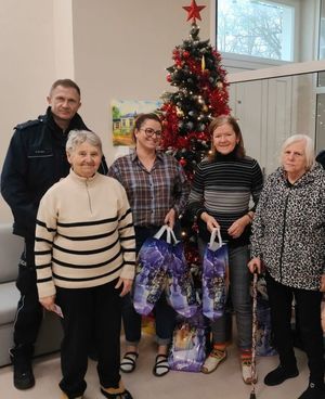 Policjant stoi z grupą podopiecznych domu pomocy przy choince.