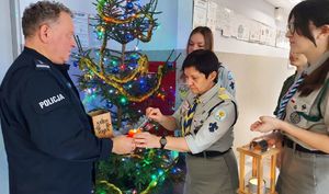 Harcerze przekazują światło pokoju komendantowi policji.