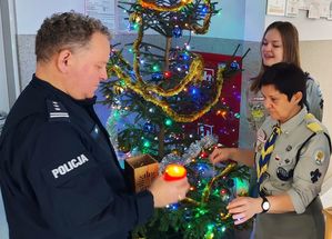 Harcerze przekazują światło pokoju komendantowi policji.