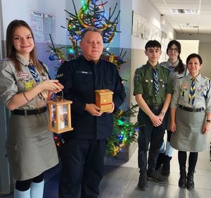 Komendant stoi z harcerzami przy choince, trzymają w dłoniach lampiony.