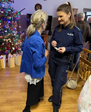 Policjantka dzieli się opłatkiem z podopiecznymi.