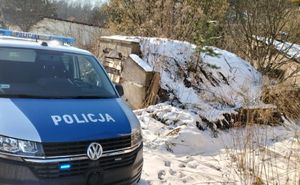 Policyjny radiowóz przy pustostanie, panuje zima.