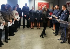 Prcownicy i policjanci stoją na sali podczas uroczystości Swięta Służby Cywilnej.