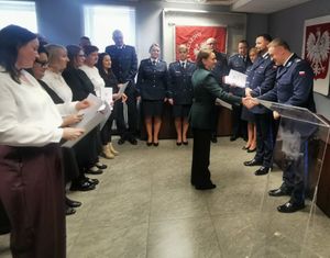 Prcownicy i policjanci stoją na sali podczas uroczystości Swięta Służby Cywilnej.