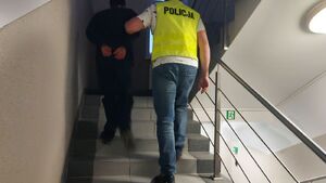 Policjant prowadzi zatrzymanego mężczyznę.