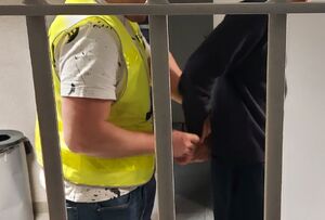 Policjant prowadzi zatrzymanego mężczyznę.