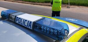 Policjant stoi przy radiowozie.