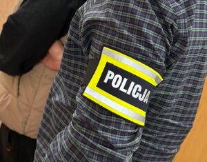 Policjant prowadzi zatrzymanego mężczyznę.