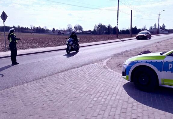 Policjantka wskazuje miejsce do zatrzymania się motocykliście.